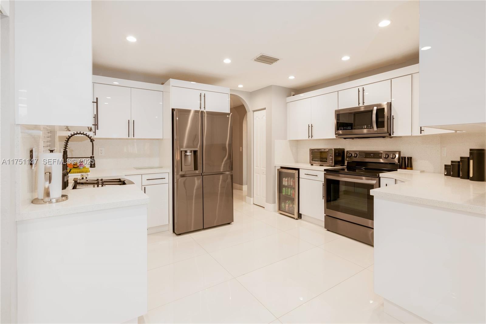 19444 Northwest 79th Court Hialeah, FL 33015 - Photo 2 of 26 a kitchen with kitchen island a refrigerator and a sink