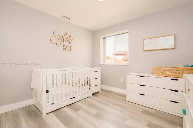 a view of a bedroom with baby crib and wooden floor