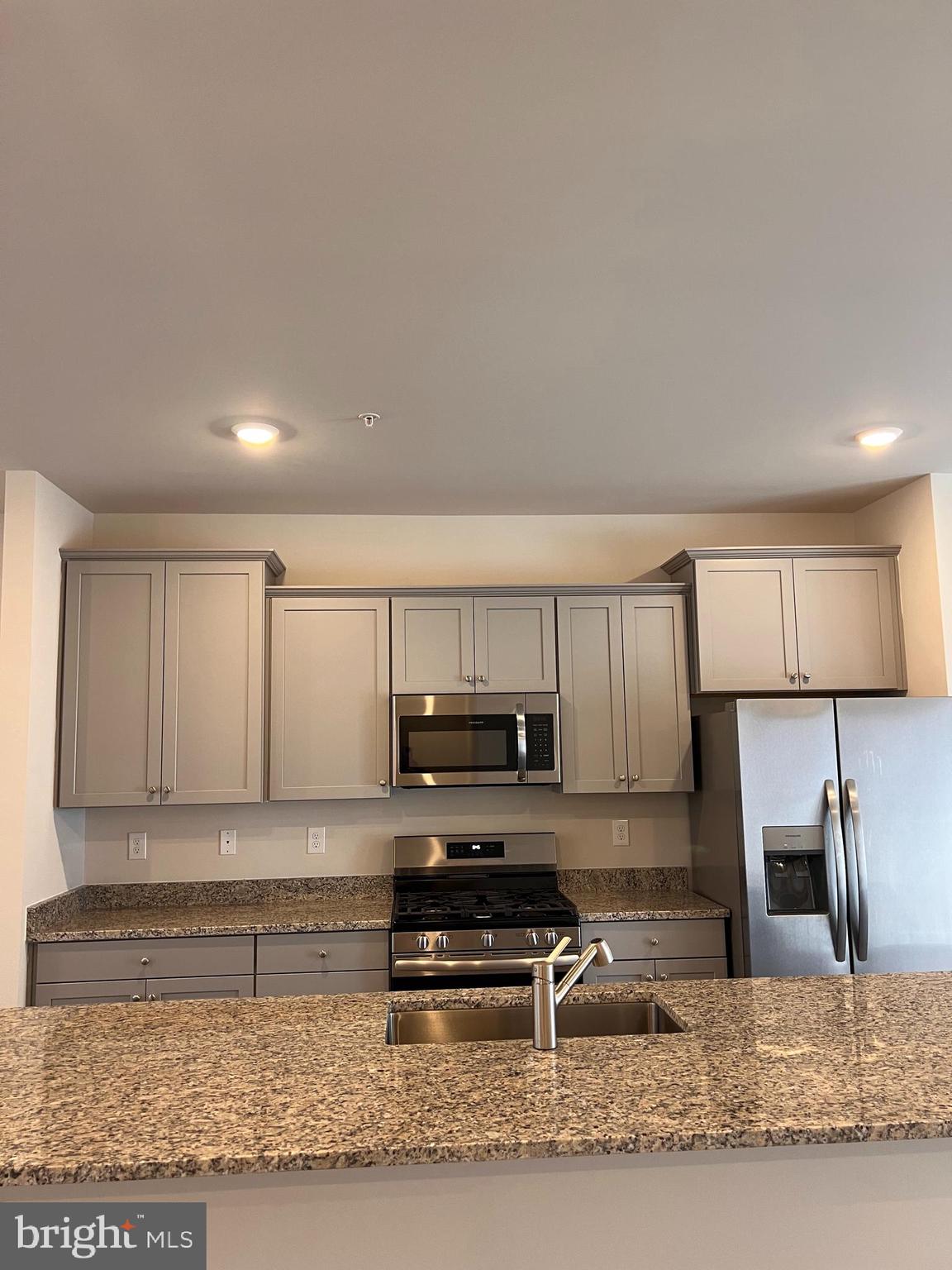 13927 Anderson Garden Road Laurel, MD 20707 - Photo 20 of 31 a kitchen with kitchen island granite countertop a stove a sink and a microwave