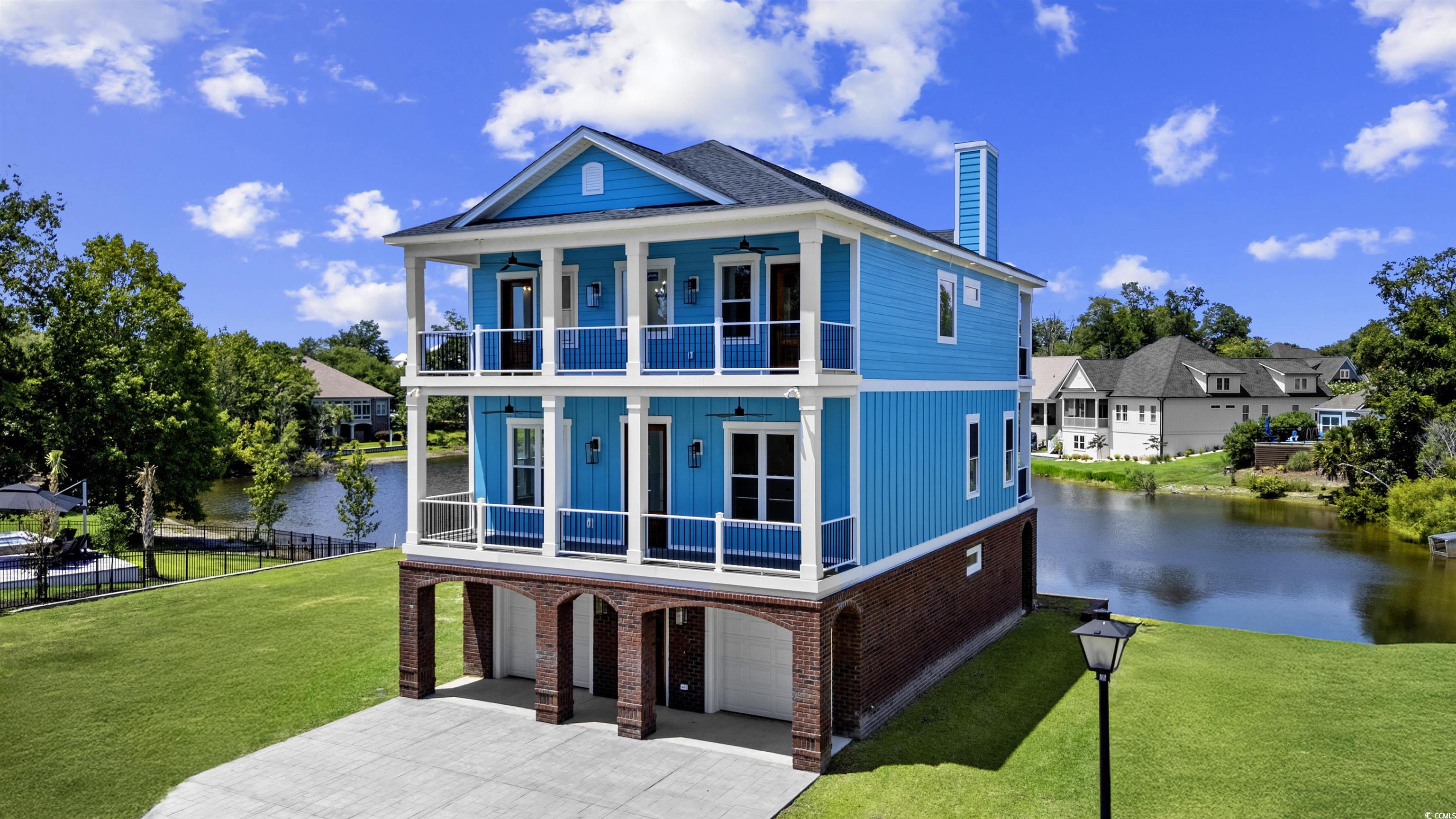 Front of house with a balcony, a water view, a garage, brick siding, and concrete driveway