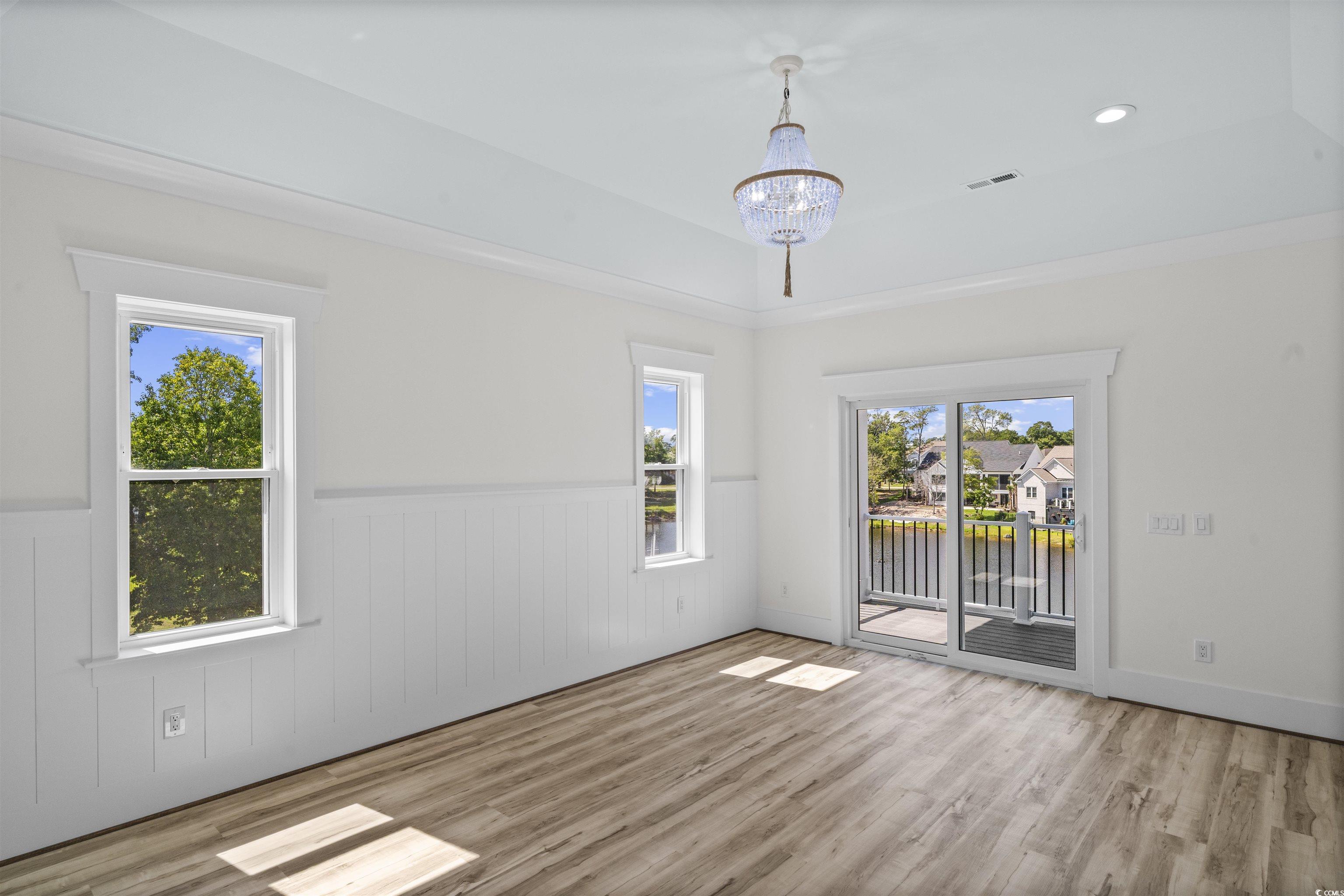 1017 Hyatt Pond Road North Myrtle Beach, SC 29582 - Photo 12 of 39 Master Bedroom featuring a chandelier, a wainscoted wall, wood finished floors, and a water view