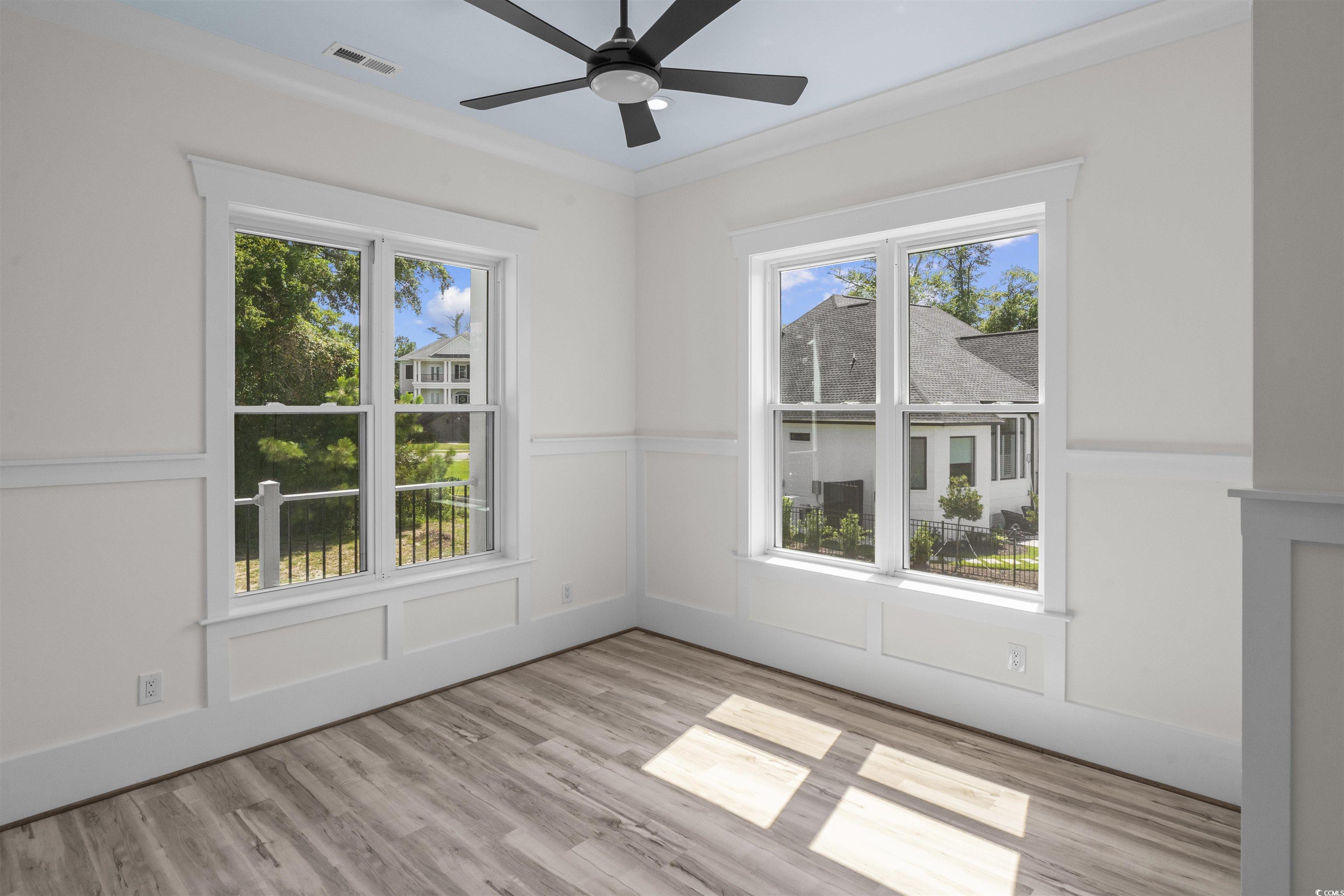 1017 Hyatt Pond Road North Myrtle Beach, SC 29582 - Photo 17 of 39 Master Bedroom featuring light wood-style flooring, ornamental molding, healthy amount of natural light, a ceiling fan, and a wainscoted wall