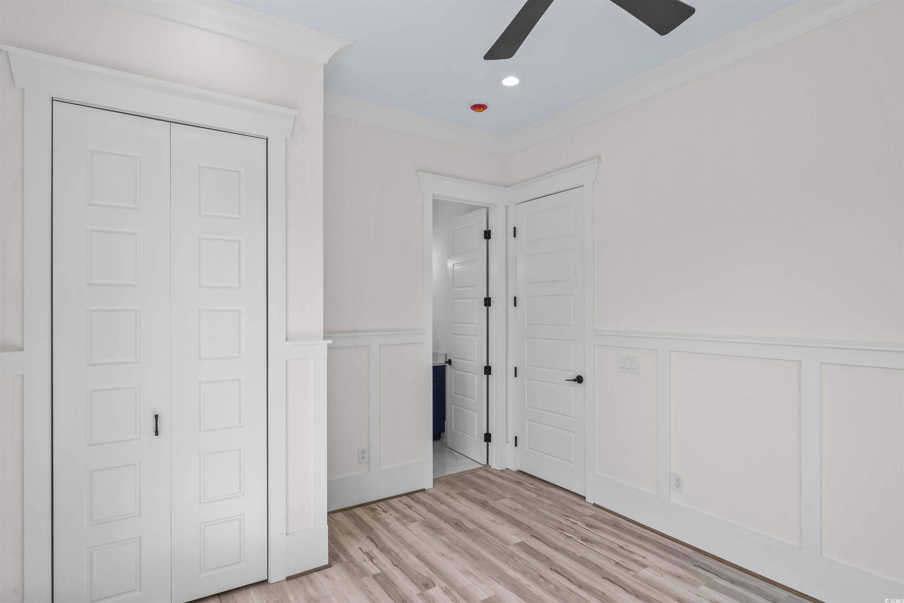 1017 Hyatt Pond Road North Myrtle Beach, SC 29582 - Photo 18 of 39 Unfurnished bedroom featuring a decorative wall, ornamental molding, light wood-style flooring, a wainscoted wall, and a closet