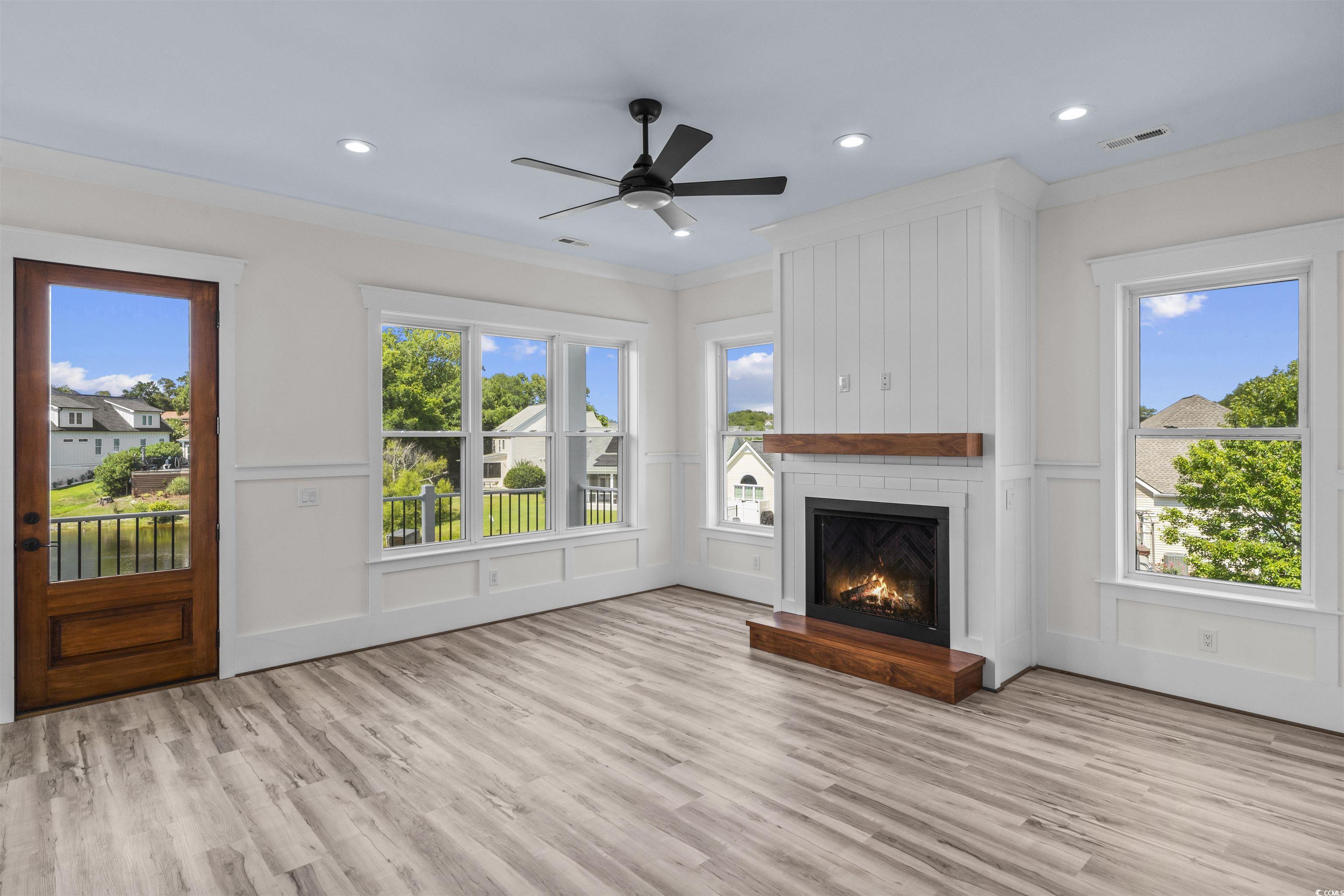 1017 Hyatt Pond Road North Myrtle Beach, SC 29582 - Photo 2 of 39 Unfurnished living room with a decorative wall, wood finished floors, a large fireplace, crown molding, and a ceiling fan