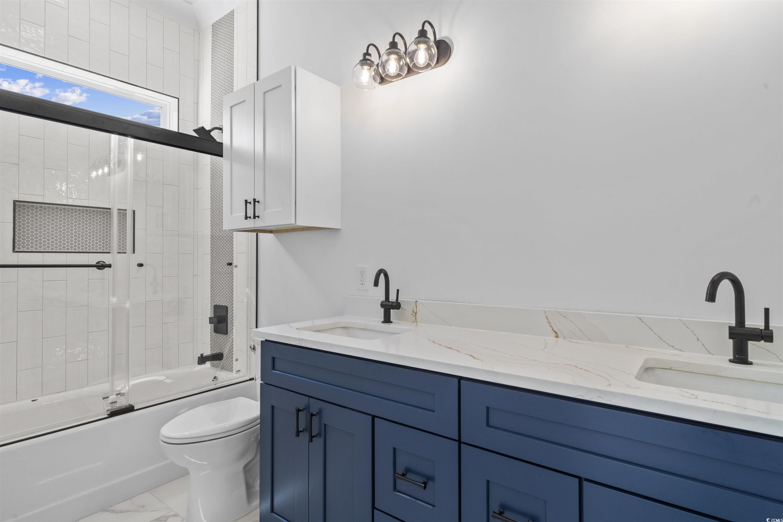 1017 Hyatt Pond Road North Myrtle Beach, SC 29582 - Photo 22 of 39 Bathroom featuring marble look tile flooring, shower / bath combination with glass door, and double vanity