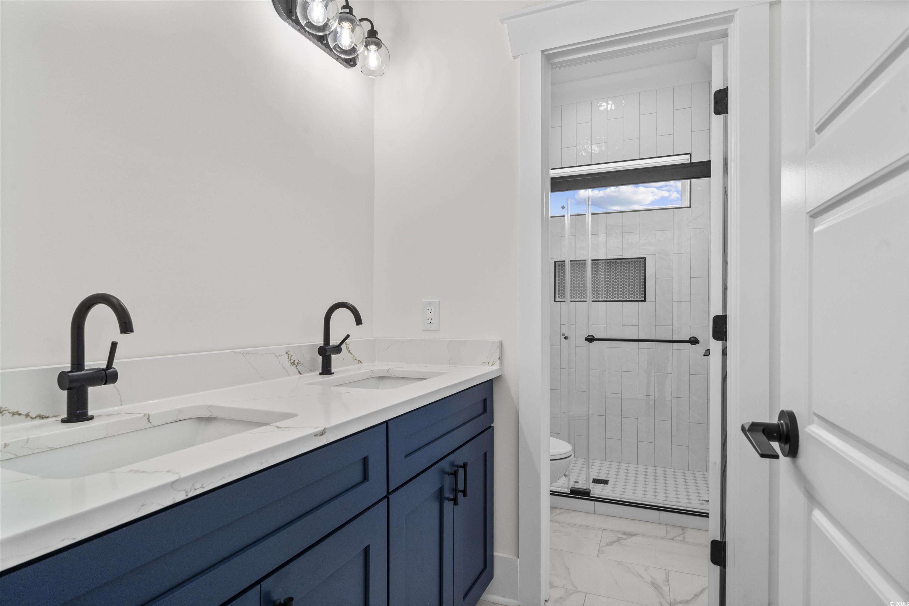 1017 Hyatt Pond Road North Myrtle Beach, SC 29582 - Photo 23 of 39 Bathroom featuring marble look tiles, a stall shower, and double vanity
