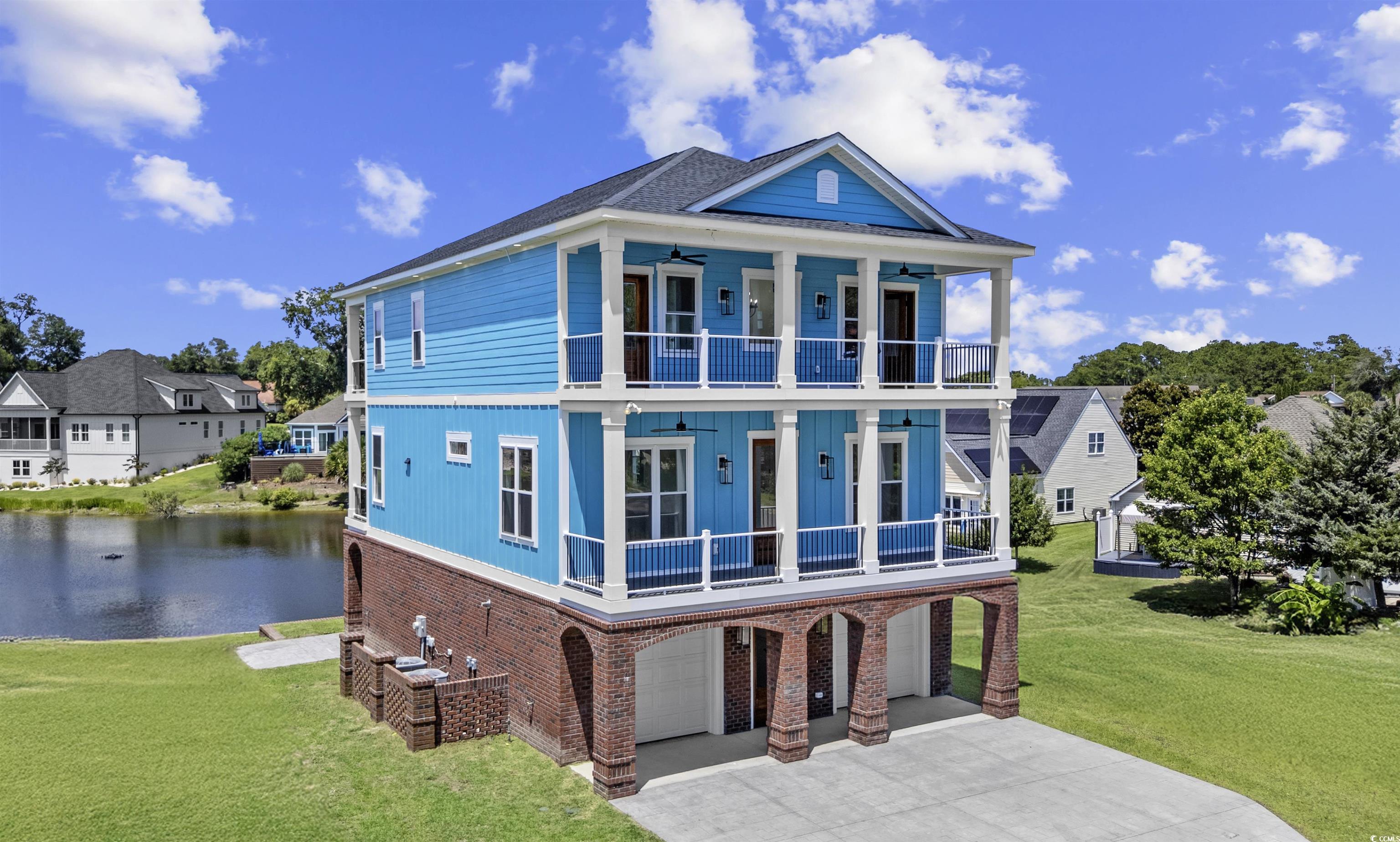 1017 Hyatt Pond Road North Myrtle Beach, SC 29582 - Photo 32 of 39 View of front of house with a balcony, a garage, a water view, a front lawn, and concrete driveway
