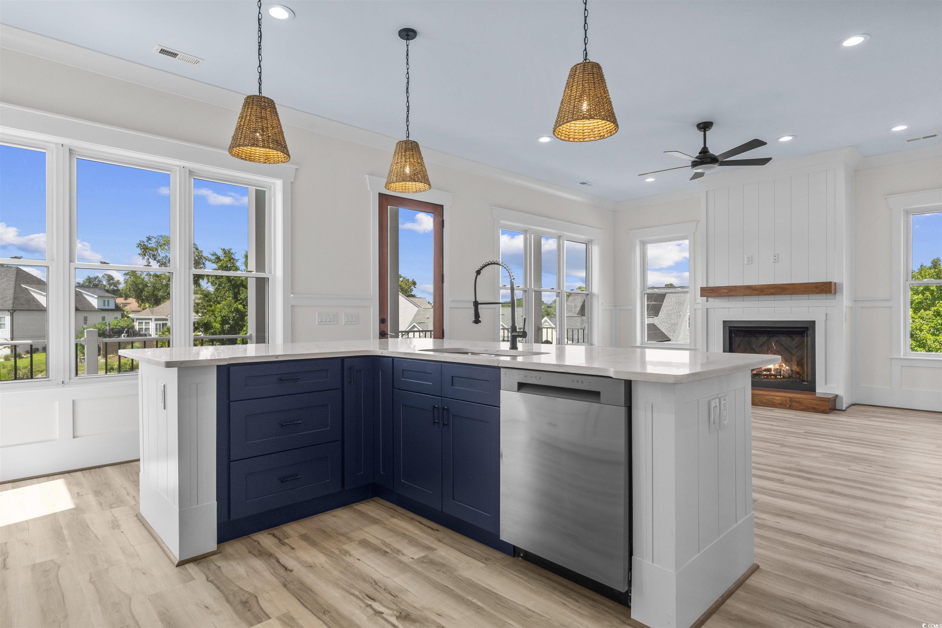 1017 Hyatt Pond Road North Myrtle Beach, SC 29582 - Photo 5 of 39 Kitchen with stainless steel dishwasher, light countertops, ceiling fan, a large fireplace, and light wood-style floors, Living room with fireplace and ceiling fan