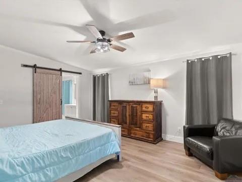 429 Private Road Big Sandy, TX 75755 - Photo 18 of 24 Bedroom with a barn door, wood finished floors, and a ceiling fan
