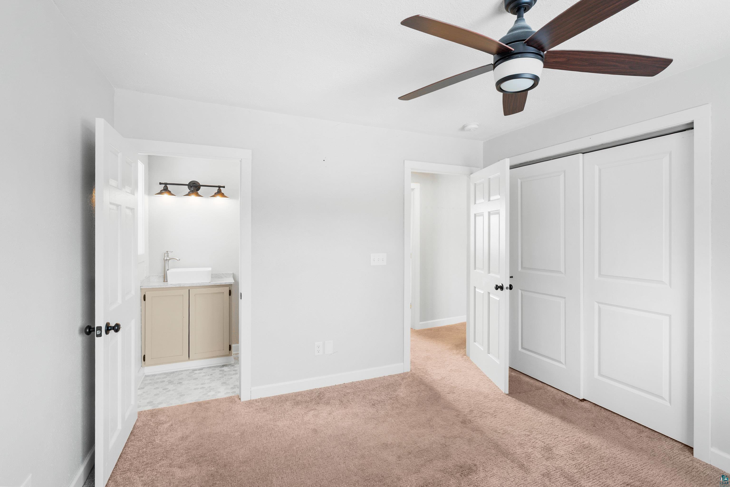 524 14th Avenue Two Harbors, MN 55616 - Photo 13 of 36 Unfurnished bedroom featuring light colored carpet, ceiling fan, a closet, and ensuite bathroom