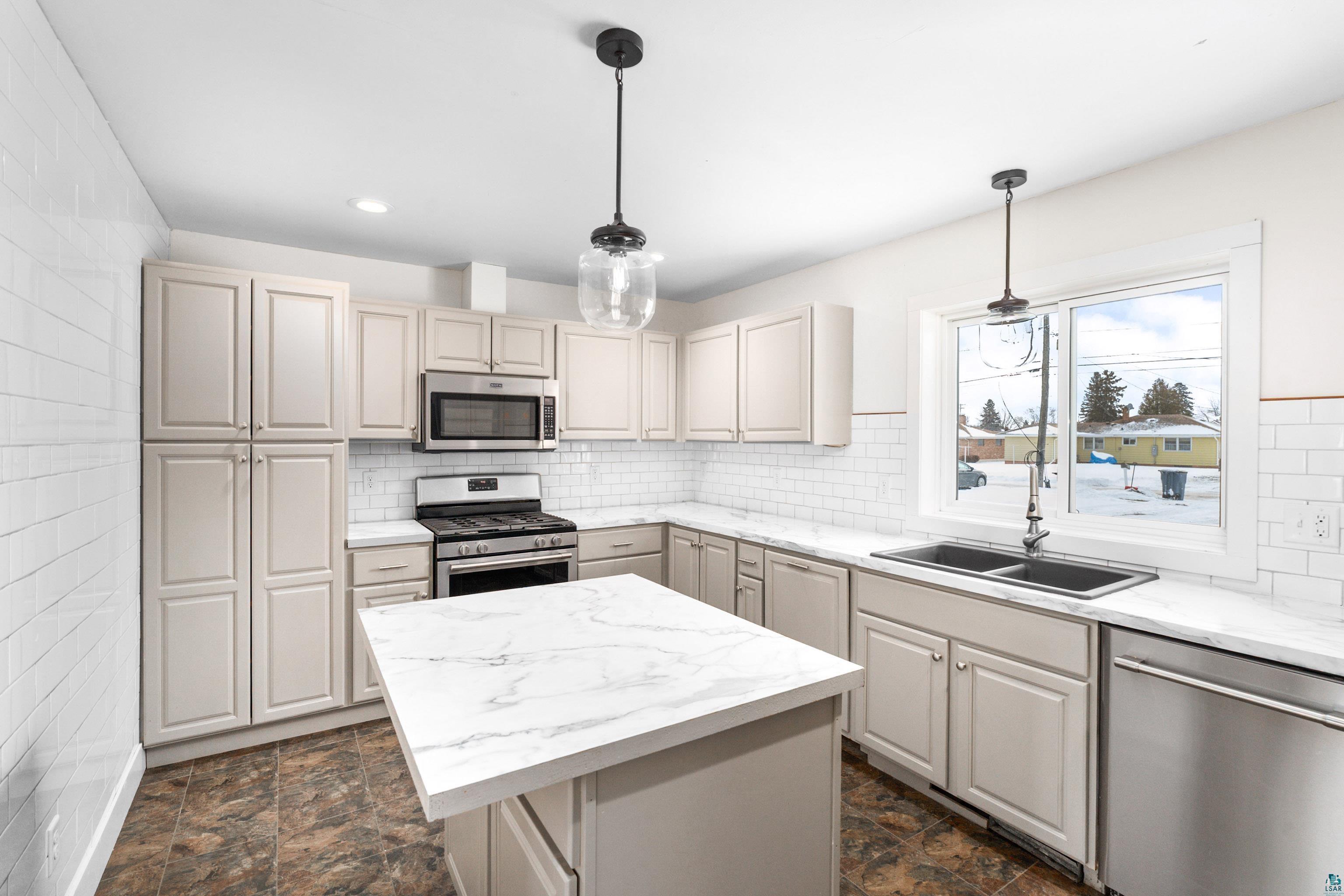 524 14th Avenue Two Harbors, MN 55616 - Photo 6 of 36 Kitchen featuring appliances with stainless steel finishes, a center island, hanging light fixtures, stone finish flooring, and recessed lighting