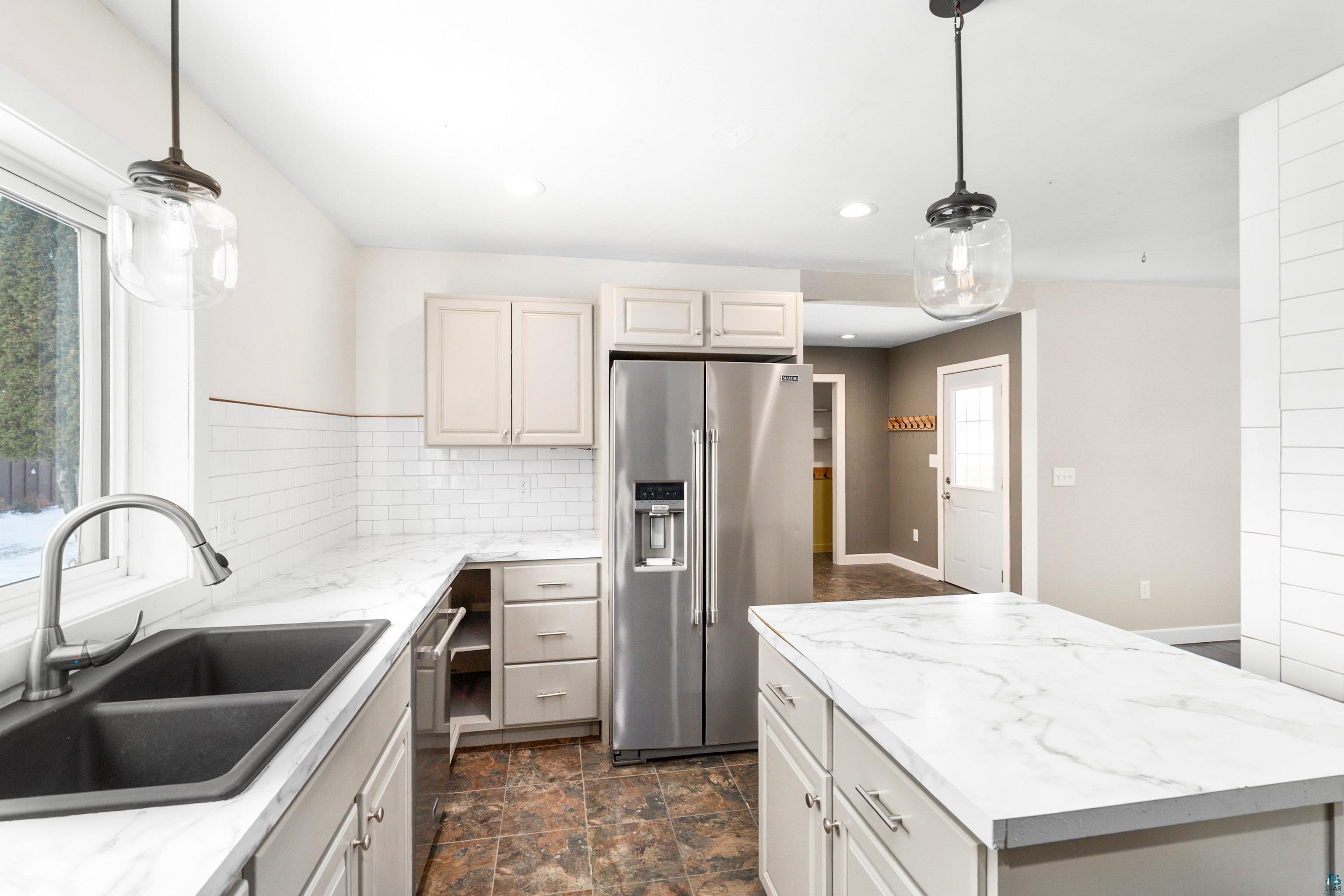 524 14th Avenue Two Harbors, MN 55616 - Photo 7 of 36 Kitchen with a kitchen island, stainless steel appliances, hanging light fixtures, stone finish flooring, and plenty of natural light