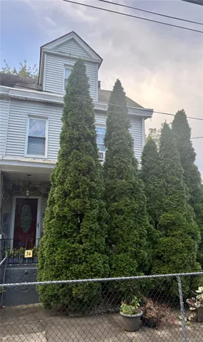 a view of a white house with large trees and plants