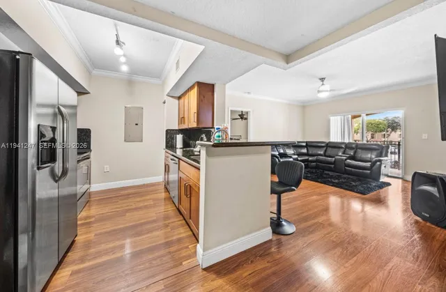 a kitchen with stainless steel appliances granite countertop a refrigerator a sink dishwasher a stove and white countertops with wooden floor