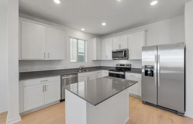 a kitchen with kitchen island a sink appliances and cabinets