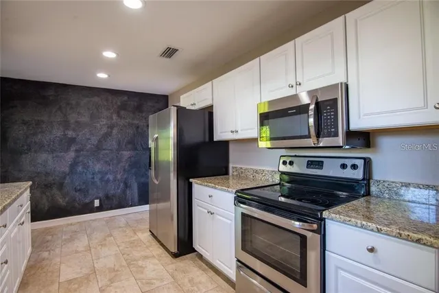 a kitchen with stainless steel appliances granite countertop a stove a refrigerator and a microwave