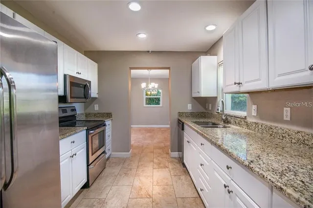 a open kitchen with granite countertop a sink dishwasher stove and refrigerator