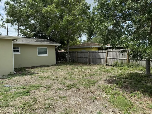 a backyard of a house with large trees and wooden fence