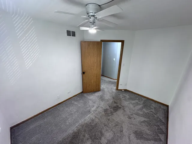 an empty room with closet and a ceiling fan