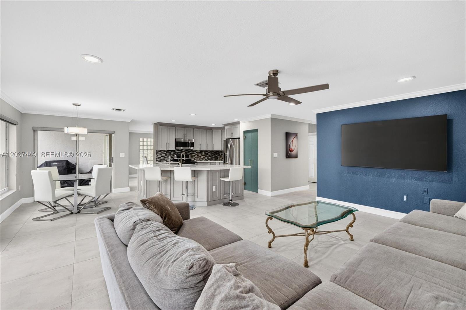 17488 Southwest 28th Court Miramar, FL 33029 - Photo 13 of 50 a living room with furniture and a flat screen tv with kitchen view