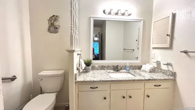 a bathroom with a granite countertop toilet sink and mirror