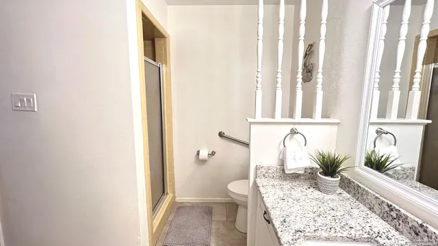 a bathroom with a granite countertop sink a toilet and shower