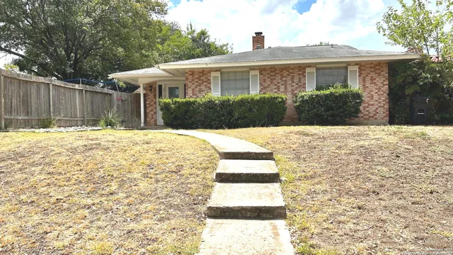 a view of house with backyard and trees in the background