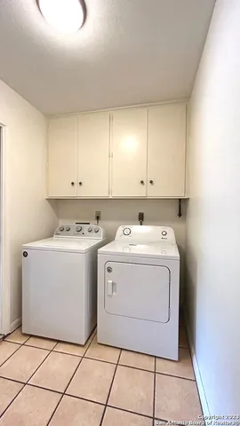 a utility room with a washer dryer and white cabinets