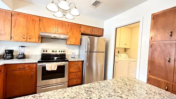 a kitchen with stainless steel appliances granite countertop a refrigerator a stove and a sink