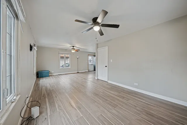 a view of empty room with wooden floor and ceiling fan