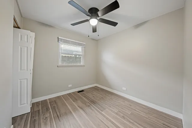 an empty room with a window and a ceiling fan