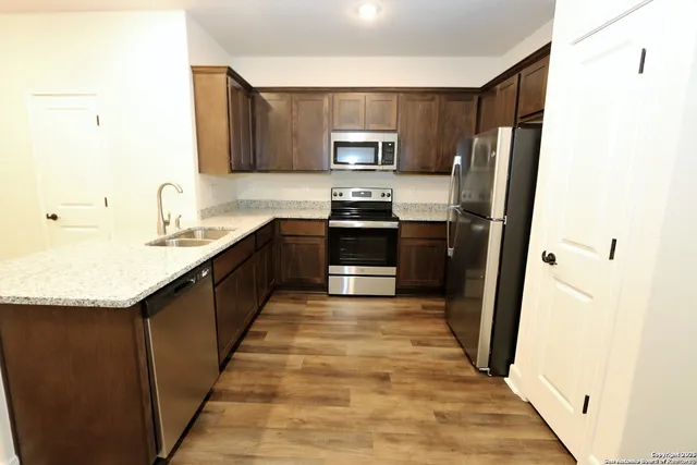 a kitchen with stainless steel appliances granite countertop a refrigerator a stove top oven a sink and dishwasher