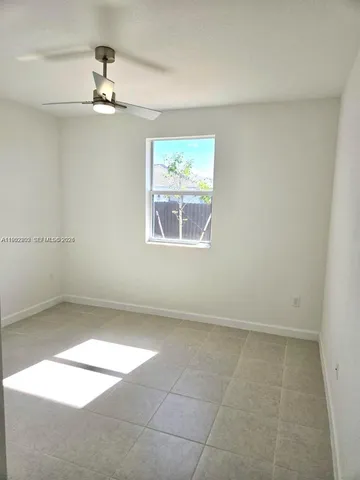 en empty room with windows and chandelier fan