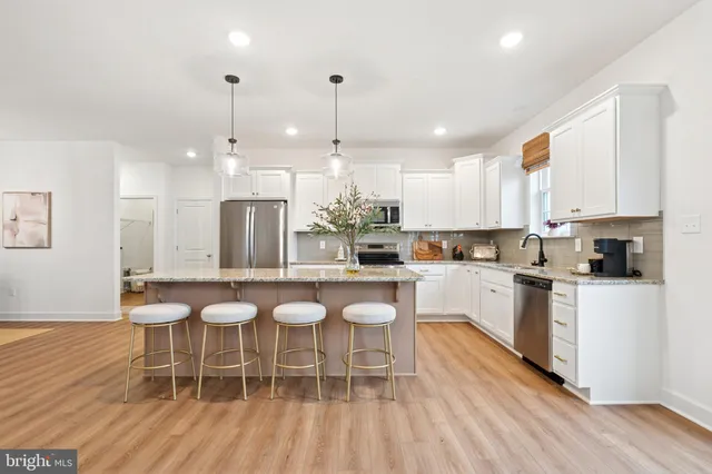 a kitchen with stainless steel appliances a dining table chairs a sink and dishwasher a refrigerator with wooden floor