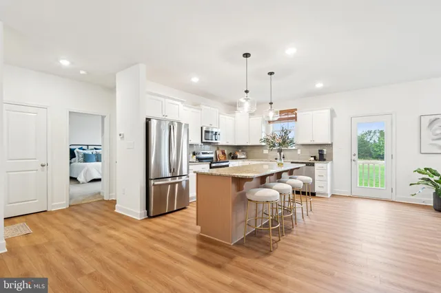 a kitchen with a refrigerator a stove top oven a sink dishwasher and white cabinets with wooden floor