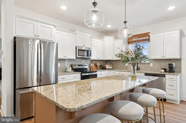 a kitchen with granite countertop a refrigerator a stove a sink a center island and furniture