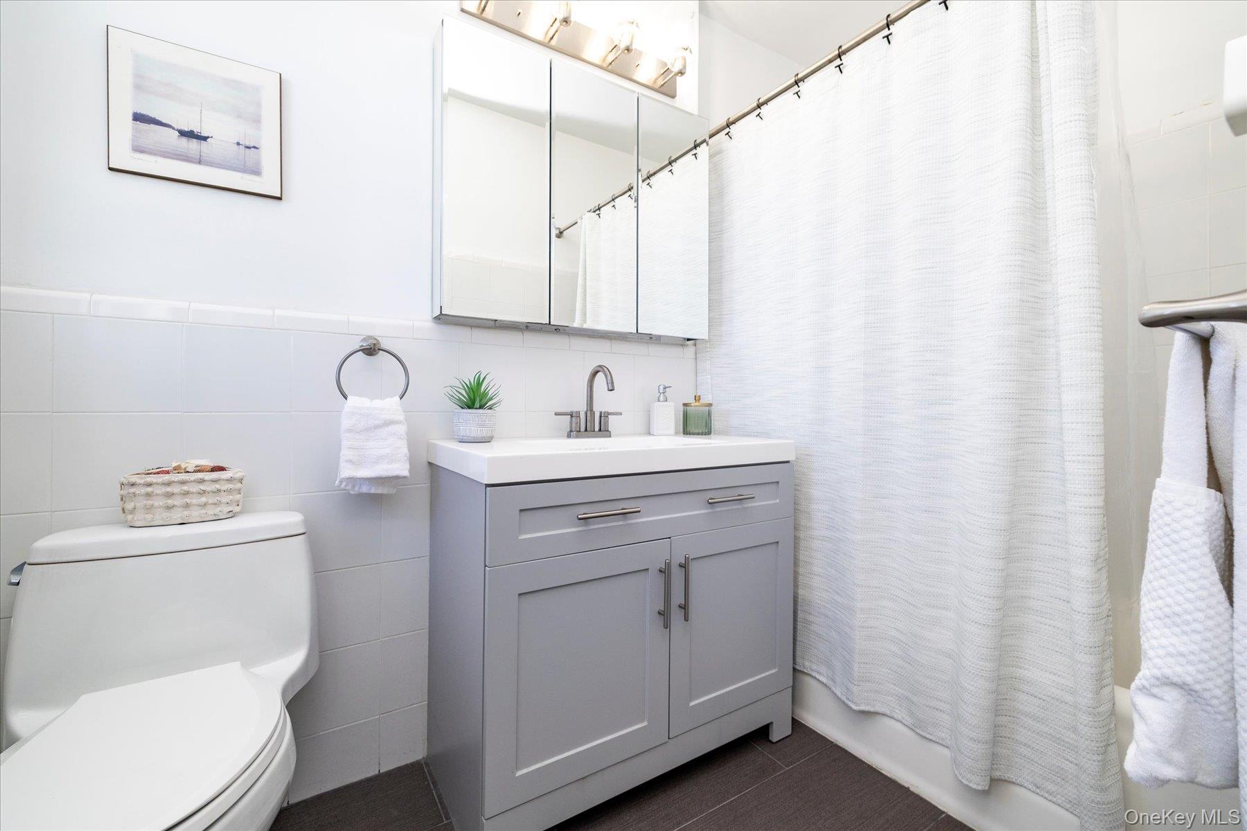 8 Barstow Road, Unit 4J Great Neck, NY 11021 - Photo 10 of 17 a bathroom with a sink a toilet and a mirror