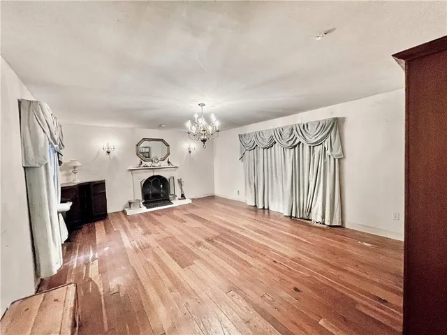 a view of a livingroom with a fireplace a ceiling fan and wooden floor