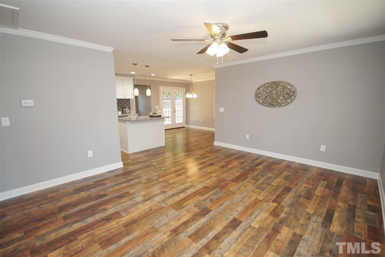 2717 Knowles Street Raleigh, NC 27603 - Photo 3 of 26 an empty room with a kitchen view and wooden floor
