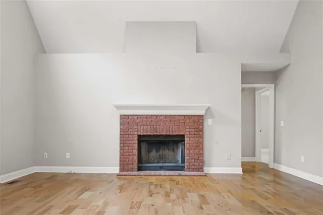a kitchen with kitchen island granite countertop a stove a sink and white cabinets with wooden floor