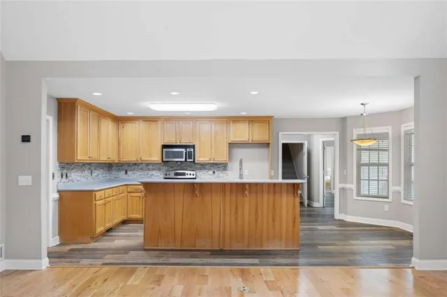 a kitchen with stainless steel appliances granite countertop wooden cabinets a sink and dishwasher a stove with wooden floor