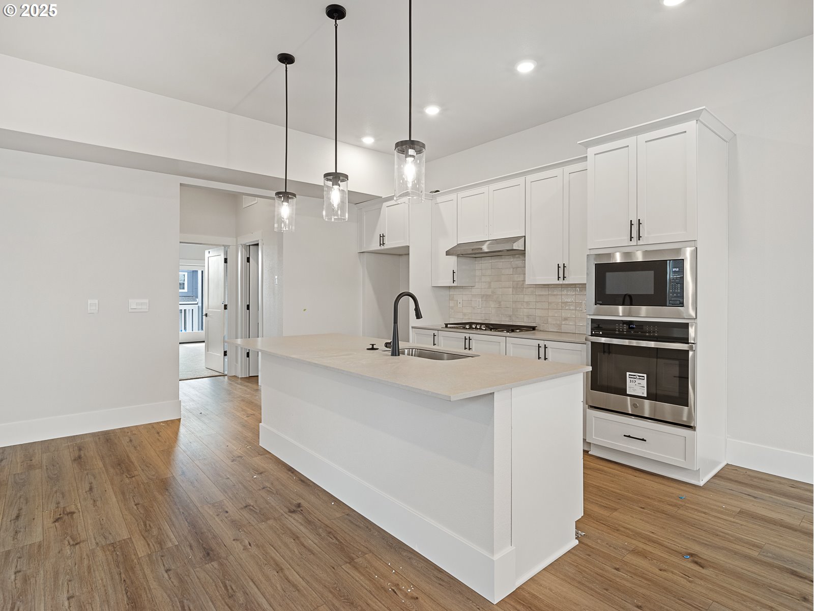 18045 Southwest Monashee Lane Beaverton, OR 97007 - Photo 6 of 45 a large kitchen with kitchen island a stove a sink dishwasher a refrigerator and white cabinets with wooden floor