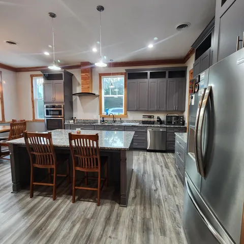 a kitchen with stainless steel appliances granite countertop a refrigerator a stove a sink and a dining table with wooden floor