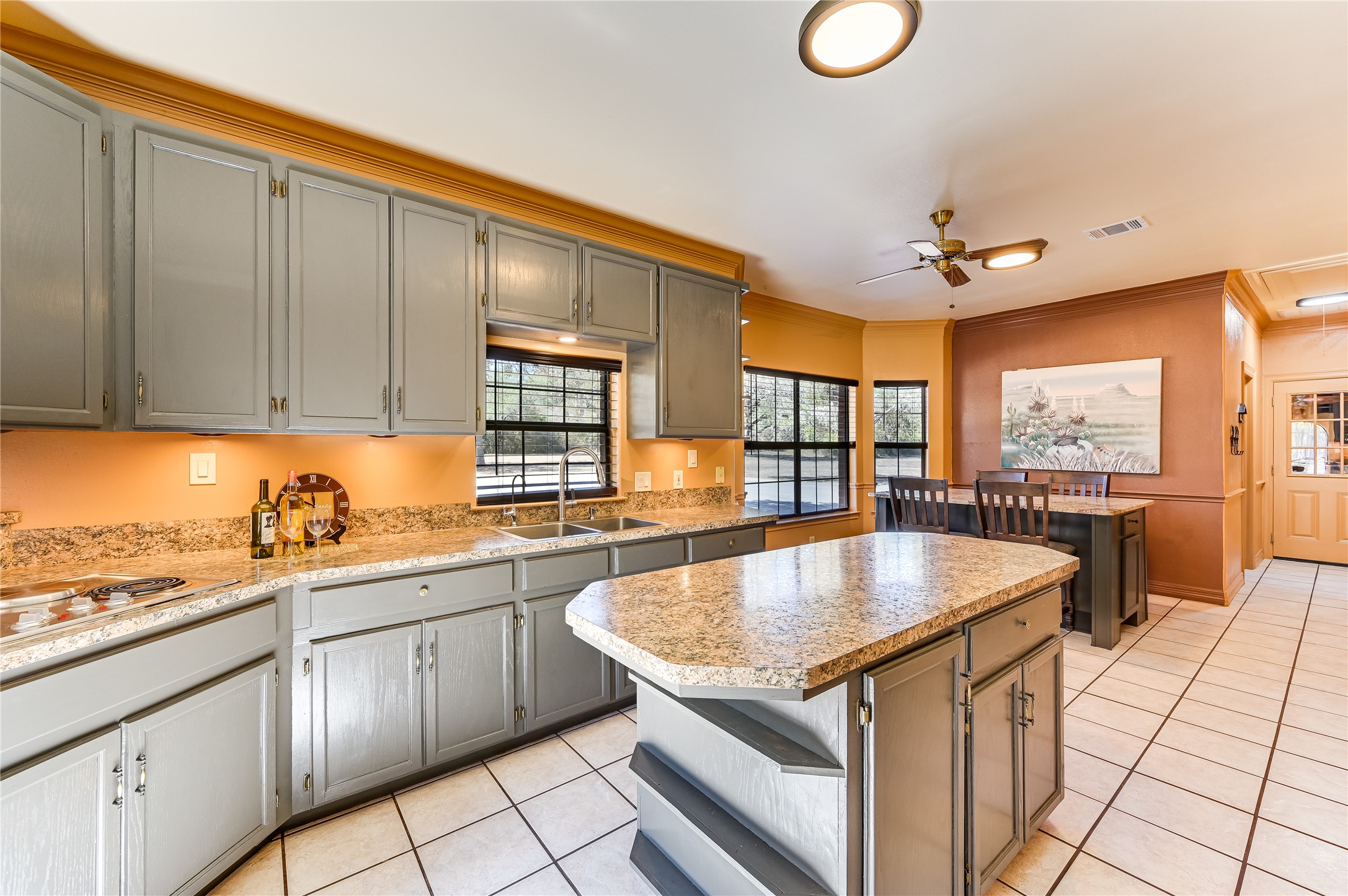 486 Westwood Road Lockhart, TX 78644 - Photo 10 of 29 Kitchen featuring gray cabinets, a center island, light tile floors, crown molding, and a large eating area