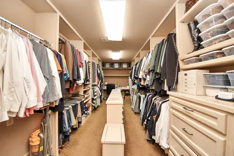 a view of a walk in closet with clothes and shoes