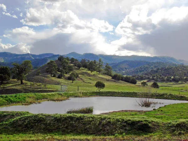 a view of green field with mountains in the background