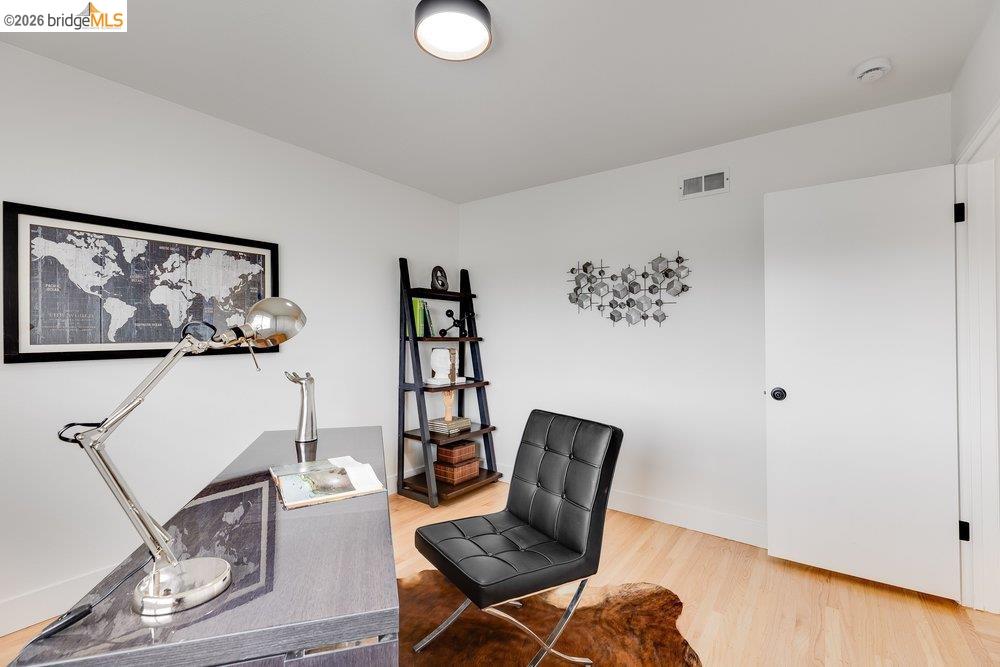 1298 Ribbon Street Foster City, CA 94404 - Photo 48 of 86 Light wood-finish flooring complements white walls in this room, featuring a solid white door with black hardware, a ceiling-mounted light fixture, and a built-in wall vent