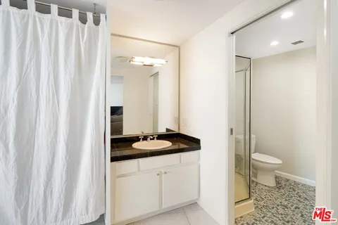 a bathroom with a granite countertop sink toilet and shower