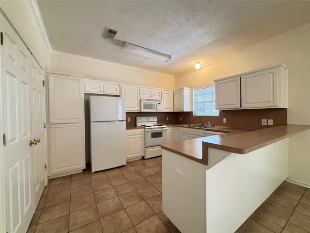 a kitchen with a refrigerator a stove top oven and white cabinets