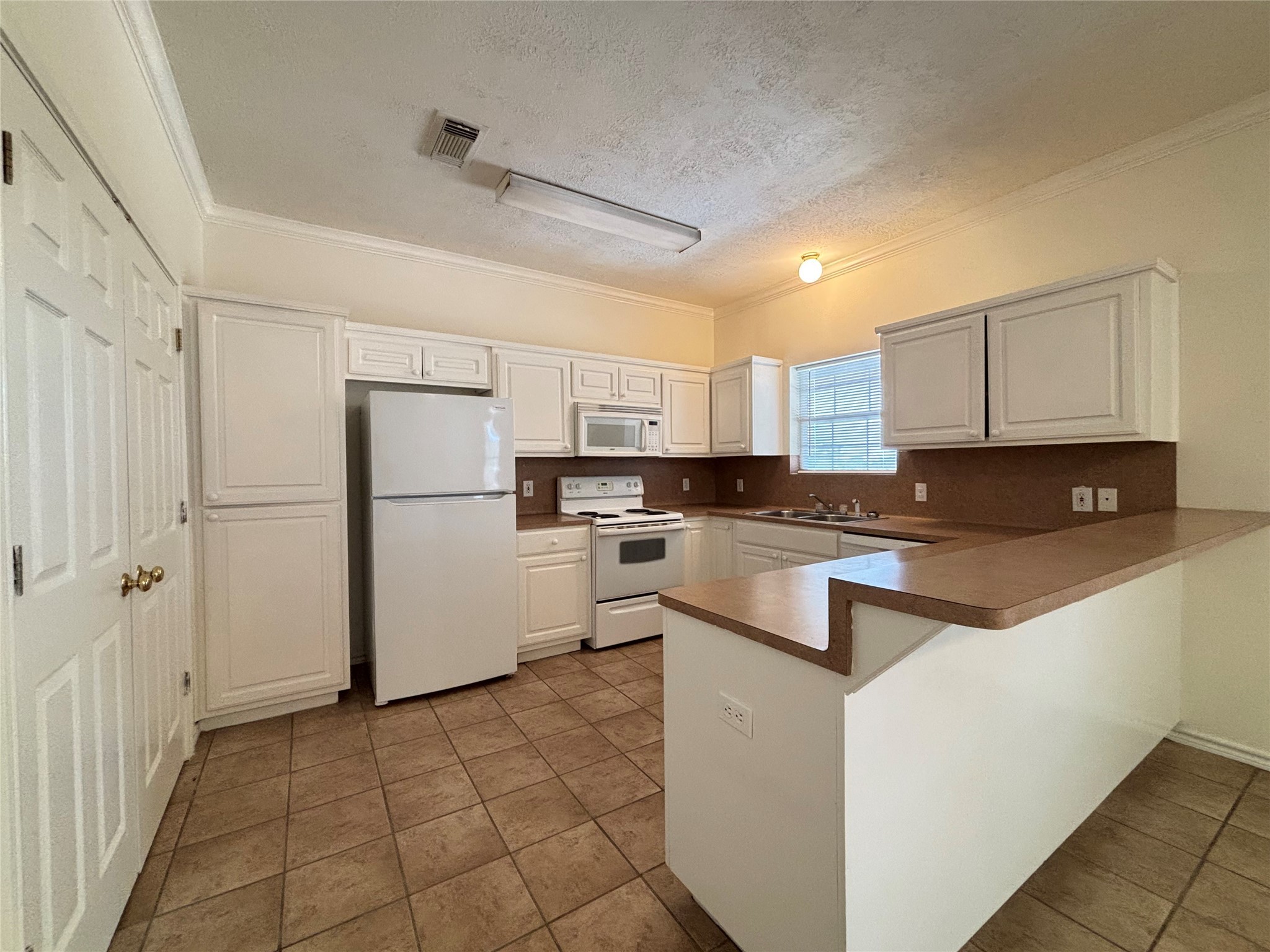 2455 Montgomery Road Huntsville, TX 77340 - Photo 3 of 10 a kitchen with a refrigerator a stove top oven and white cabinets